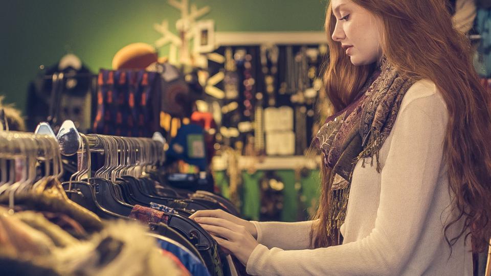 Vásárló ruhákat néz végig egy bolti állványon — a kínálat online megfelelője a terméklista